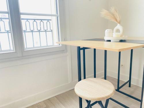 een tafel en een kruk in een kamer met een raam bij Charmant studio calme, proche La Défense & Paris in La Garenne-Colombes