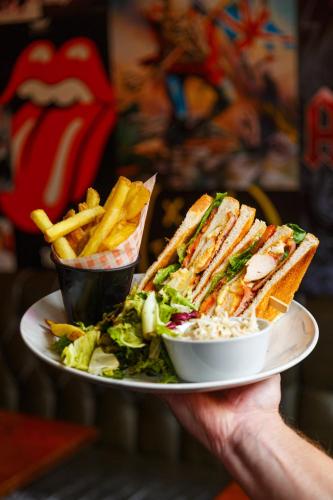 a person holding a plate with a sandwich and french fries at The Saddle Inn in Chester