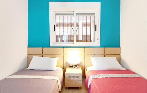 Duas camas num quarto com paredes azuis e uma janela em Awesome Apartment In Oropesa Del Mar With Swimming Pool em Oropesa del Mar