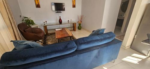 a living room with a blue couch and a table at Three Stones Executive Apartments in Maseru