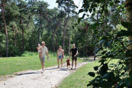 a group of people walking a dog on a path at Familie vakantiepark Krieghuusbelten in Raalte