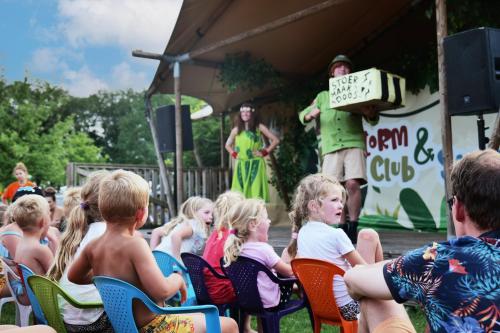 een groep kinderen die in stoelen zitten te kijken naar een performer bij Familie vakantiepark Krieghuusbelten in Raalte