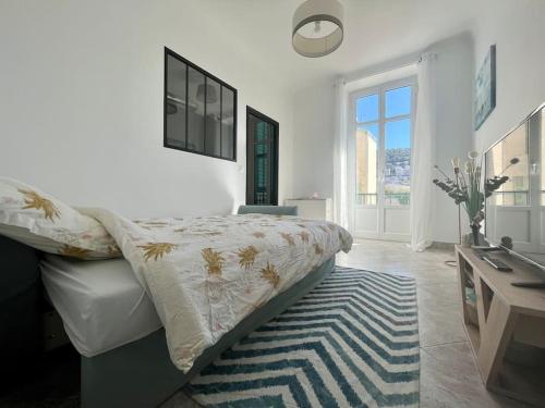 a white bedroom with a bed and a desk and a window at 2 pièces cocooning près du port/gare riquier in Nice
