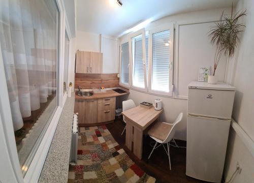 uma pequena cozinha com uma mesa e um frigorífico em Kineski zid em Zenica