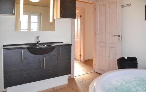 W łazience znajduje się umywalka, lustro i wanna. w obiekcie Lovely Home In Tarm With Kitchen w mieście Fjerbæk