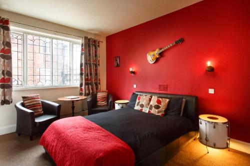 a red bedroom with a bed and a guitar on the wall at The Saddle Inn in Chester