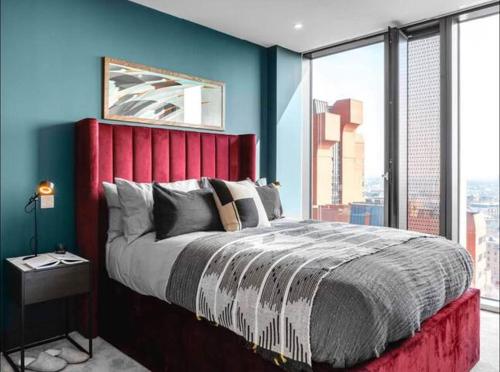 a bedroom with a large bed with a red headboard at The Mercian Luxury Apartments Birmingham City Centre - Your Perfect Stay Apart hotels- 24 Hour Gym Rooftop Terrace Cinema Room in Birmingham