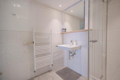 ein weißes Bad mit einem Waschbecken und einer Dusche in der Unterkunft SEEZEIT Residence in Hagnau