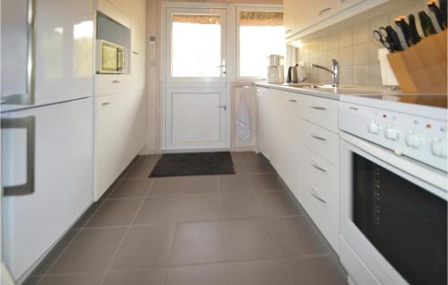 HavrvigにあるNice Home In Hvide Sande With Kitchenの白いキャビネットとシンク付きのキッチン