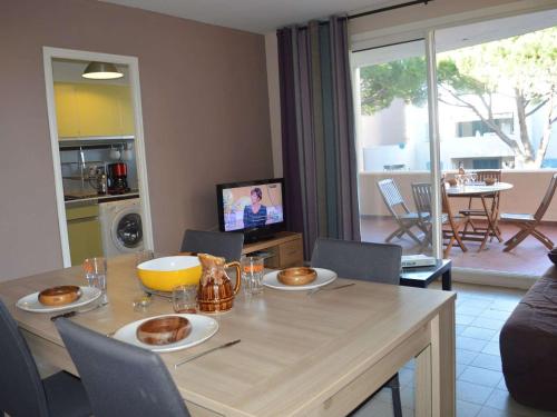 un salon avec une table avec des chaises et une télévision dans l'établissement Studio mezzanine 4 couchages à Cavalaire avec terrasse, ascenseur, lave-vaisselle et lave-linge - FR-1-226B-27, à Cavalaire-sur-Mer