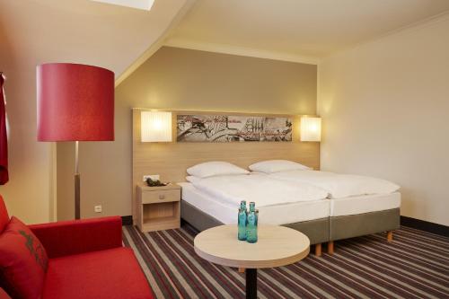 a hotel room with a bed and a red couch at Sunday Hotel Stade Herzog Widukind in Stade