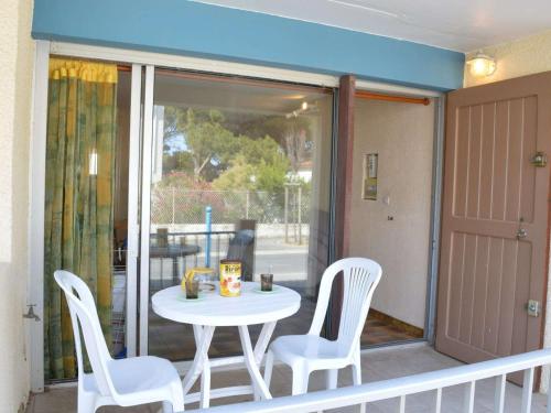 une table et des chaises blanches sur un balcon avec une table et des chaises dans l'établissement Studio en RDC à 250m de la plage - Saint Pierre la Mer, 2 couchages, animaux acceptés - FR-1-229D-232, à Saint Pierre La Mer