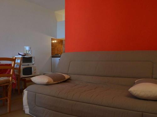 - un salon avec un canapé et un mur rouge dans l'établissement Appartement T2 à Saint Pierre la Mer, proche plage, loggia sud, parking, animaux acceptés - FR-1-229D-272, à Saint Pierre La Mer