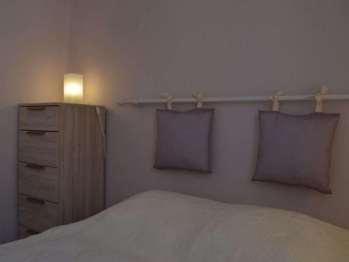- une chambre avec un lit et une commode avec des oreillers violets dans l'établissement Appartement T2 à Saint Pierre la Mer, proche plage, loggia sud, parking, animaux acceptés - FR-1-229D-272, à Saint Pierre La Mer