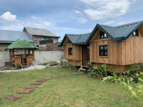 uma casa com um telhado verde e um quintal em Unlimited Pax Bale Kubo-inspired Accommodation em Tarlac