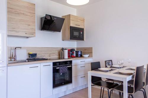 une cuisine avec une table et des placards blancs dans l'établissement ZenBNB / Scandinavian / Gare / Parking Privé /, à Annemasse