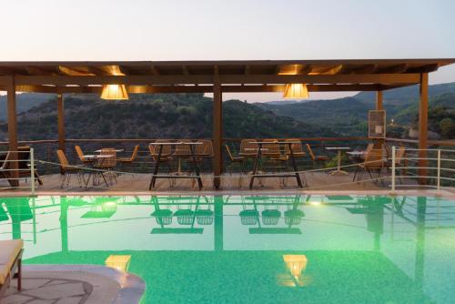 a swimming pool with chairs and tables and a mountain at Bacchus Villa in Archea Pissa