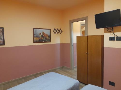 Habitación con dormitorio y TV en la pared. en Albergo Jolanda en Diano Marina