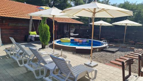 a group of chairs and umbrellas next to a pool at Odmaraliste Kod Miće Apartman 3 in Krušar