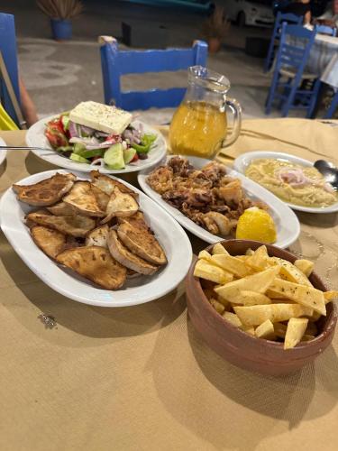 a table topped with plates of food and french fries at Rodothea and Adams on the Beach, Santorini in Monolithos