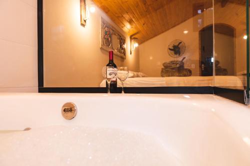 a bath tub with a bottle of wine and two glasses at Chalés das Acácias in Sana
