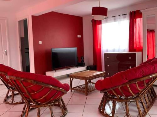 uma sala de estar com paredes e cadeiras vermelhas e uma televisão em Appartements Andrian Location em Antananarivo