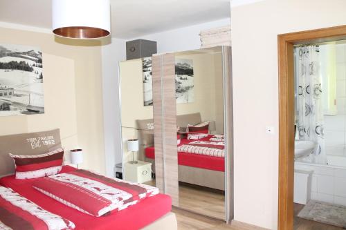 a bedroom with a red bed and a mirror at Winklmoos Sonnenalm in Reit im Winkl
