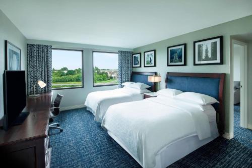 フィラデルフィアにあるシェラトン スイーツ フィラデルフィア エアポートのベッド2台とテレビが備わるホテルルームです。