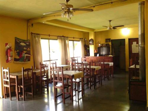 una sala da pranzo con tavoli, sedie e ventilatore a soffitto di Hotel 20 de Junio a Mina Clavero