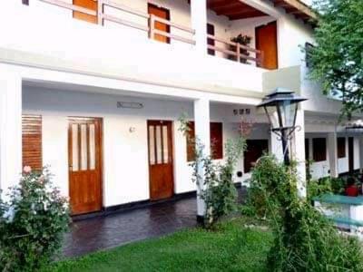 ein weißes Haus mit roten Türen und einem Balkon in der Unterkunft Hotel 20 de Junio in Mina Clavero