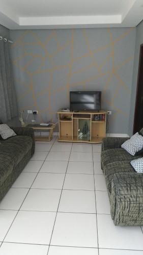 sala de estar con 2 sofás y TV de pantalla plana en Apt vista panorâmica, en Triunfo