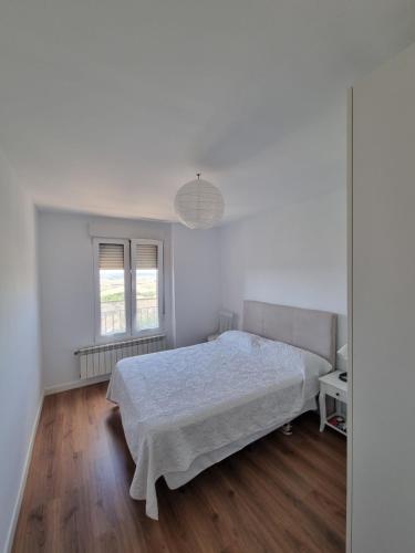 a white bedroom with a bed and a window at El Carmen in Toro