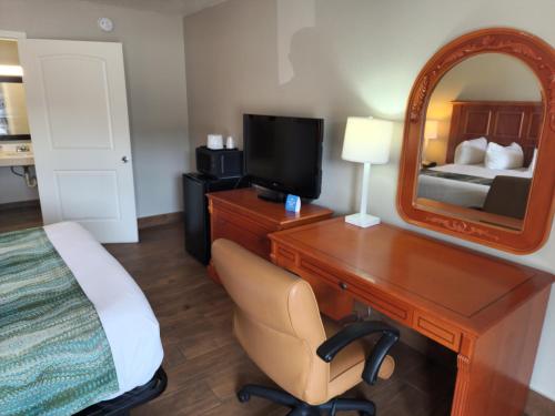a bedroom with a desk and a bed and a mirror at Days Inn by Wyndham Hardeeville Near Hilton Head in Hardeeville
