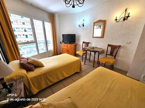 a hotel room with two beds and a television at Estudio acogedor y tranquilo en zona estupenda in Fuengirola