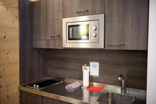 a kitchen with a sink and a microwave at DolceVita Ambiez B&B in San Lorenzo in Banale