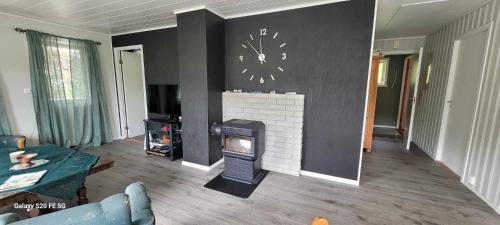 a living room with a fireplace and a clock on the wall at Lyngtun in Viksdalen