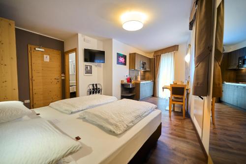 a bedroom with two beds and a kitchen with a table at DolceVita Ambiez B&B in San Lorenzo in Banale