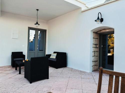 een patio met banken en stoelen aan een witte muur bij Trullo Assiolo in Valle d'Itria in Martina Franca