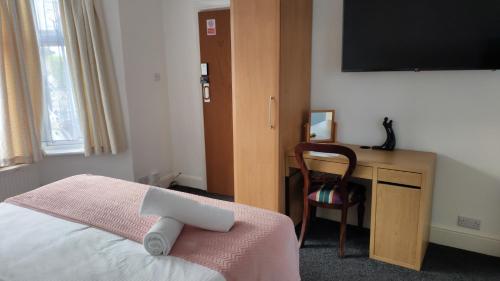 Schlafzimmer mit einem Bett und einem Schreibtisch mit einem TV in der Unterkunft Fair Oak Self-Catering Accomodation in Sandown