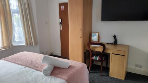 a bedroom with a bed and a desk with a television at Fair Oak Self-Catering Accomodation in Sandown