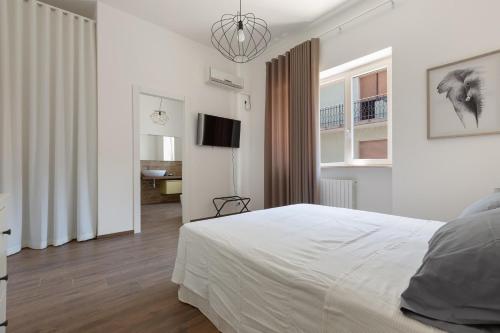 um quarto branco com uma cama e uma televisão em Casa di Rosa by BarbarHouse em Maglie