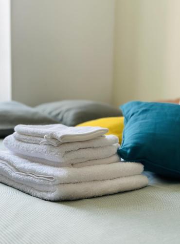 a stack of towels on a bed with a pillow at Le Charentais #Confort #RDC in Cognac