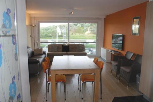 een woonkamer met een tafel en stoelen en een bank bij Lautrec in Bredene