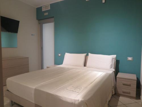 a bedroom with a large white bed with a blue wall at Appartamento QCM natura cultura e divertimento in Giulianello