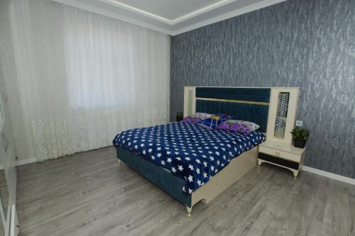 a bedroom with a bed with a blue and white comforter at Welcome Inn in Baku