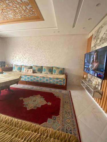 Appartement prestige في القنيطرة: غرفة معيشة مع أريكة وتلفزيون بشاشة مسطحة