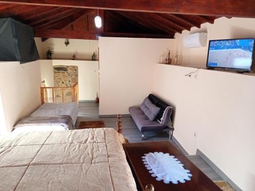 ein Schlafzimmer mit einem Bett, einem Sofa und einem TV in der Unterkunft O cantinho da Laura in Lamego