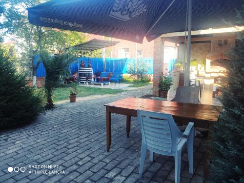 a wooden table and chairs under an umbrella on a patio at Guesthouse Mery in K'obulet'i