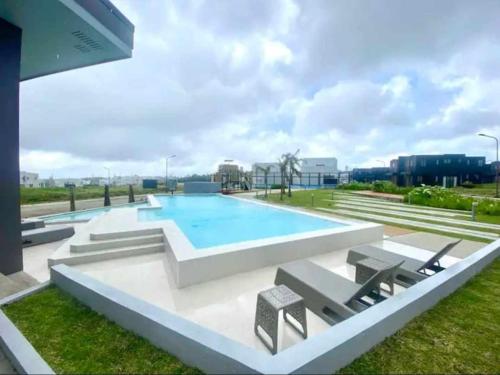 a large swimming pool with lounge chairs in a field at Cozy Holiday Home at Batulao Artscapes 2Br brand new fully airconditioned in Calo