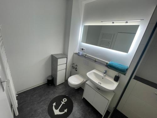 La salle de bains est pourvue d'un lavabo, de toilettes et d'un miroir. dans l'établissement Haus Weitblick Alva, à Flensbourg